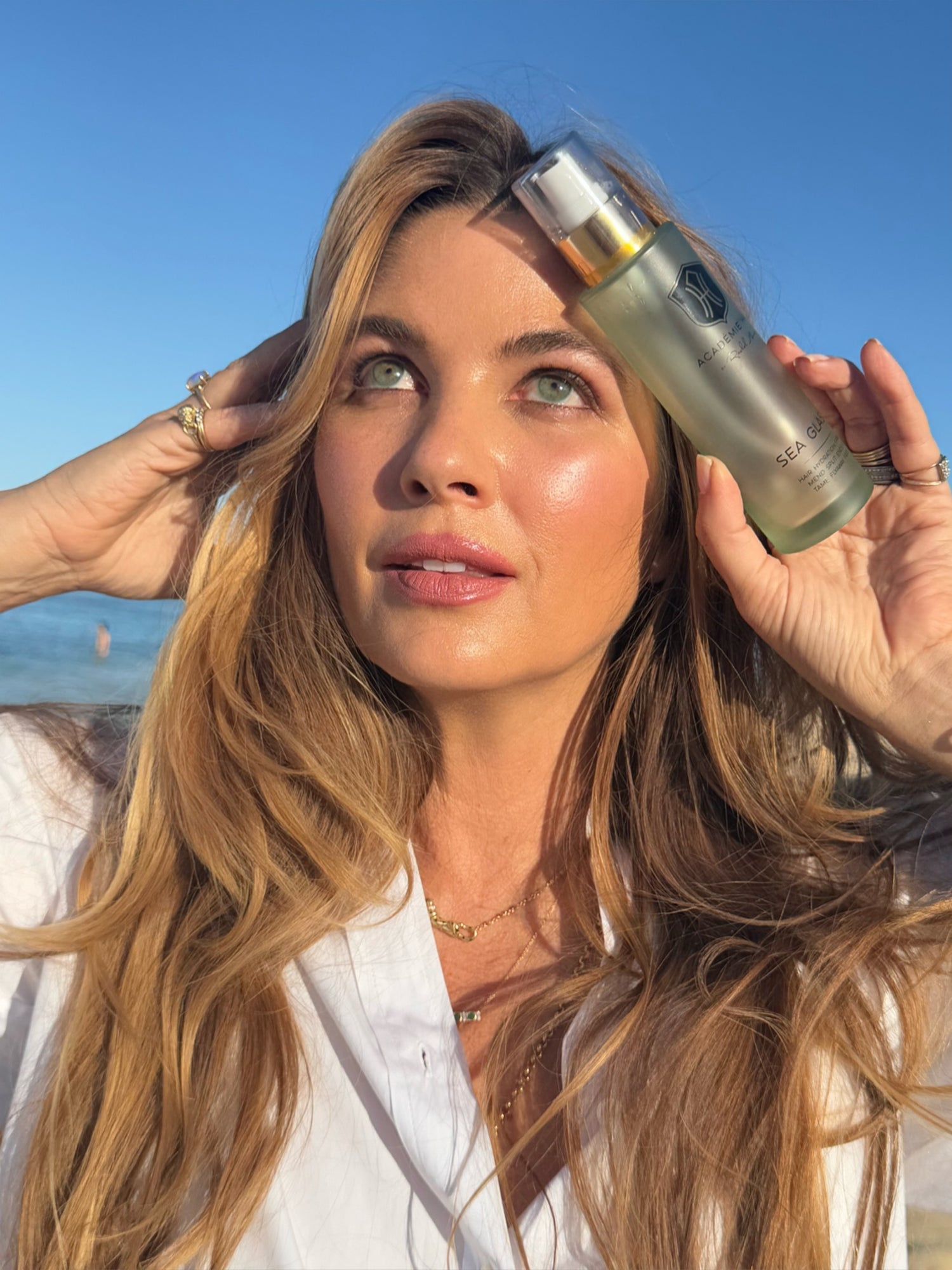 Rachel holding a bottle of Sea Glass against a blue sky